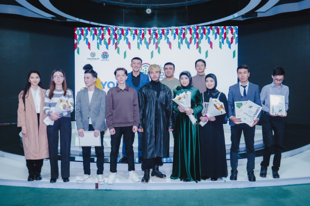 Gruppe von Menschen auf einer Bühne mit Blumensträußen und Urkunden vor dem Hintergrund "Youth Solar Awards 2019"
