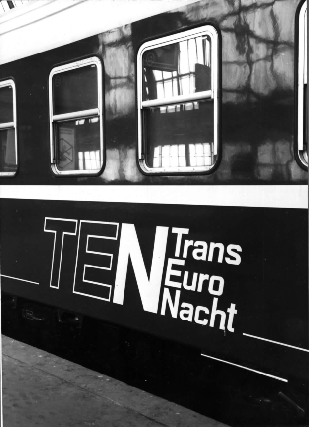 Schwarzes und weißes Foto eines Zuges mit der Aufschrift "Trans Euro Nacht" und Fenstern sowie einer Plattform darunter.