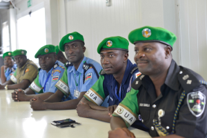 Gruppe von Polizeibeamten, die an einem Tisch während einer Schulung sitzen, mit Mobiltelefonen und anderen Gegenständen auf dem Tisch.