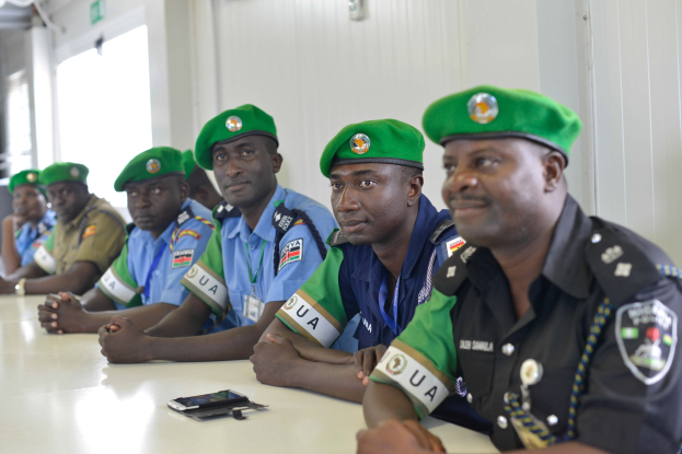 Gruppe von Polizeibeamten, die an einem Tisch während einer Schulung sitzen, mit Mobiltelefonen und anderen Gegenständen auf dem Tisch.