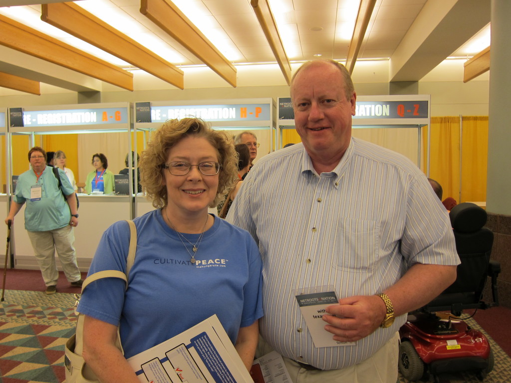 Menschen, die auf einem Boden mit einem Rollstuhl und einer Wand im Hintergrund, Decke und Lampen über ihnen stehen.