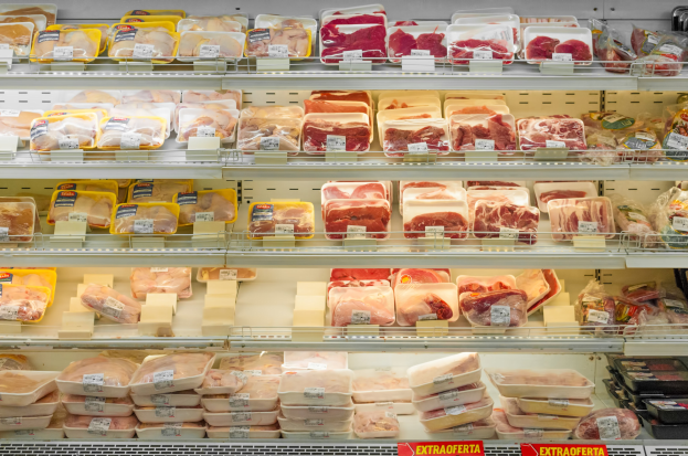 Ein gut organisierter Gem"useabteilung mit verschiedenen Fleischsorten auf Regalen, jeweils mit Preisschildern.