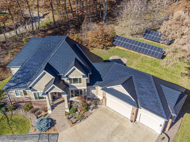 Luftaufnahme eines Hauses in North Carolina mit Solarmodulen auf dem Dach, umgeben von grünem Rasen, Pflanzen und Bäumen.