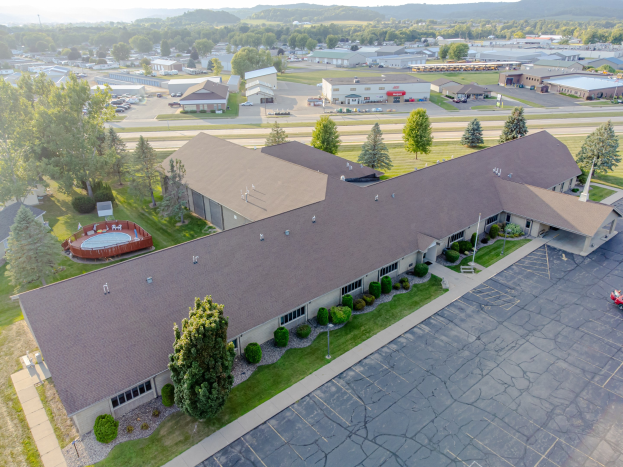 Luftaufnahme eines großen Seniorenwohnheims an der University of Kentucky, das einen Parkplatz, umliegende Grünflächen, Fahrzeuge auf der Straße, entfernte Hügel und einen klaren blauen Himmel zeigt.