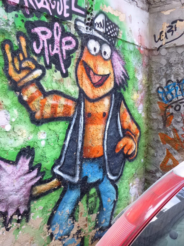 Ein rotes Auto vor einer Wand mit Graffiti geparkt.