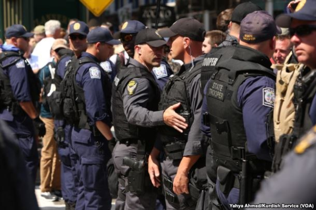 Eine Gruppe von Polizisten in Uniform, die auf einer Straße stehen, einige halten Waffen, mit Gebäuden und Schildern im Hintergrund.