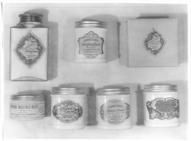 Schwarzes und weißes Foto eines Regals mit ordentlich angeordneten Cremetöpfchen, jeweils mit verschiedenen Typen beschriftet.