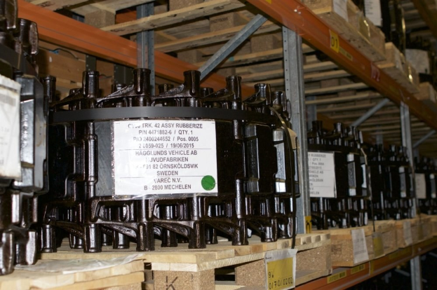 Ein Lagerhaus voller Metallobjekte auf Holzpaletten, jedes mit einem Aufkleber versehen, die Teil eines Verteilergehäuses zu sein scheinen, mit verschiedenen sichtbaren Komponenten.