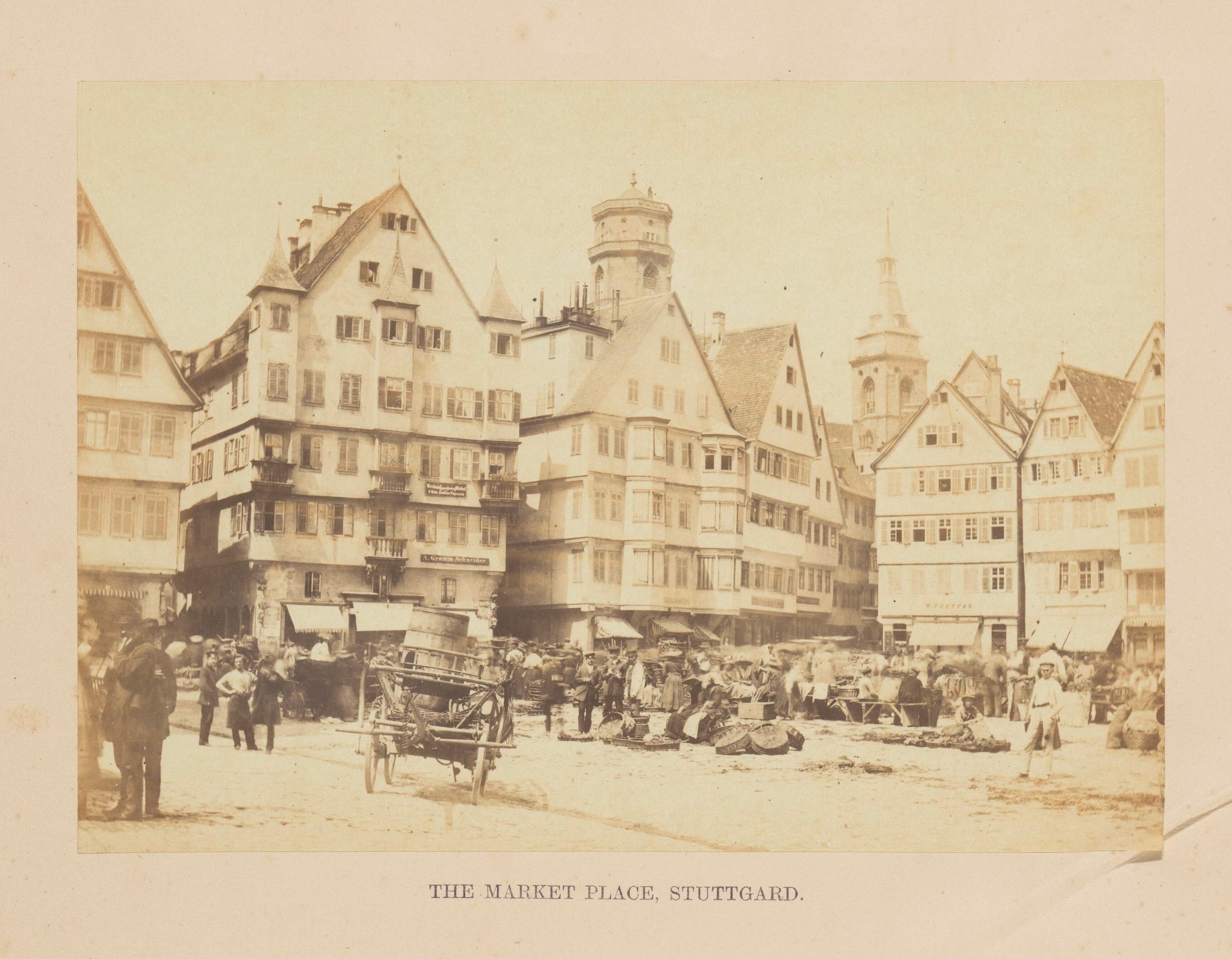 Altes Schwarz-Weiß-Foto eines belebten Marktplatzes in Stuttgart, Deutschland, mit mehrstöckigen Gebäuden, Passanten, Karren und verstreuten Waren; Text erscheint am unteren Rand.