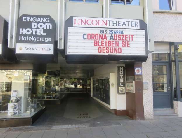 Außenansicht des Lincoln Theaters in Berlin, Deutschland, mit Glasfenstern und -türen sowie einer Tafel und einem durch die Fenster sichtbaren Innenraum mit verschiedenen Gegenständen.