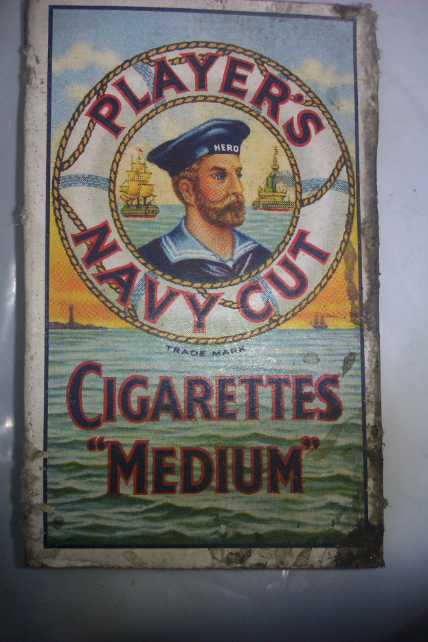 Ein Vintage-Plakat mit einer Person in einer marineblauen Uniform mit weißem Hemd und roter Krawatte, die Arme verschränkt und mit ernstem Gesichtsausdruck, neben schwarzer, fetter Schrift, die 'Player's Navy Cut Cigarettes Medium' in einem weißen Rahmen lautet.