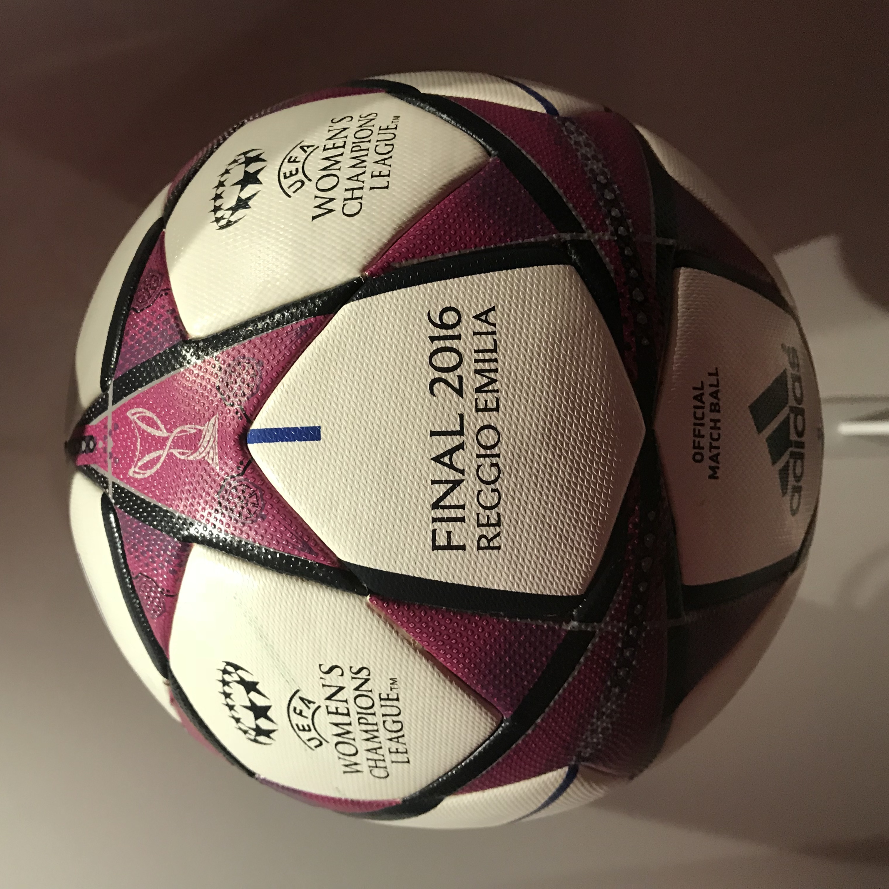 Ein Füßball auf einem weißen Tisch mit der Aufschrift "UEFA Women's Champions League Final 2016" in Weiß, Rosa und Schwarz.