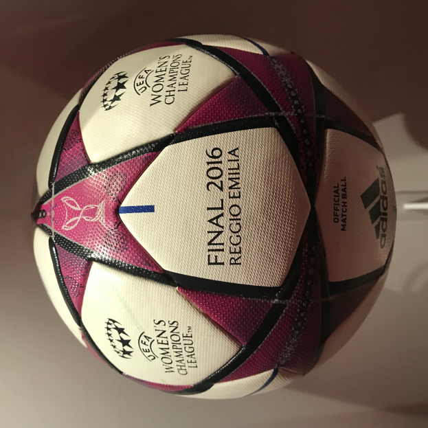 Ein Füßball auf einem weißen Tisch mit der Aufschrift "UEFA Women's Champions League Final 2016" in Weiß, Rosa und Schwarz.