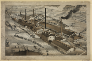 Ein altes Schwarz-Weiß-Bild der Omaha und Grant Smelting Company-Fabrik mit Rauch, der aus ihren Schornsteinen aufsteigt, umgeben von Gebäuden und Fahrzeugen.