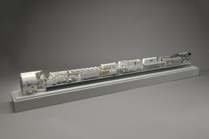 Ein detailliertes Modell eines Sainsbury-Hydrogen-Brennstoffzellensystems, das miteinander verbundene Komponenten wie einen Kraftstofftank, ein Filter und eine Einspritzdüse auf einer weißen Oberfläche zeigt.