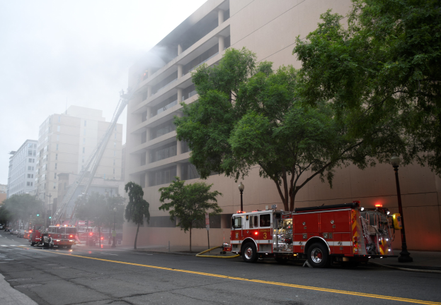 Feuerwehrfahrzeuge auf einer Stadtstraße mit Bäumen und Gebäuden geparkt, wahrscheinlich nach einem Wohnungsbrand in San Francisco.