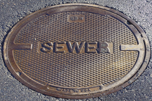 Eine Metall-Schachtohle auf der Straße mit der geprägten Aufschrift "Kanal"