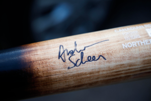 Ein Close-up eines hölzernen Hockey-Schlägers mit einer Signatur und Text darauf.