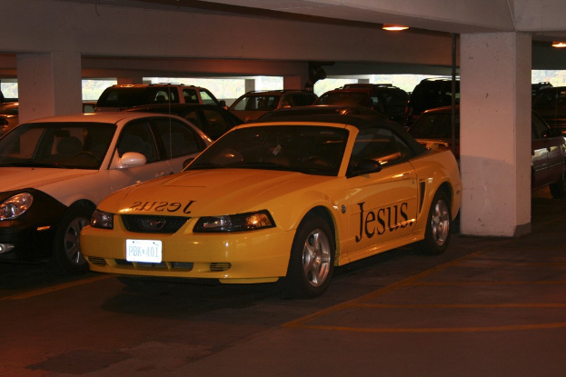 Ein vollgestellter Parkplatz mit zahlreichen Autos vor einem Gebäude.