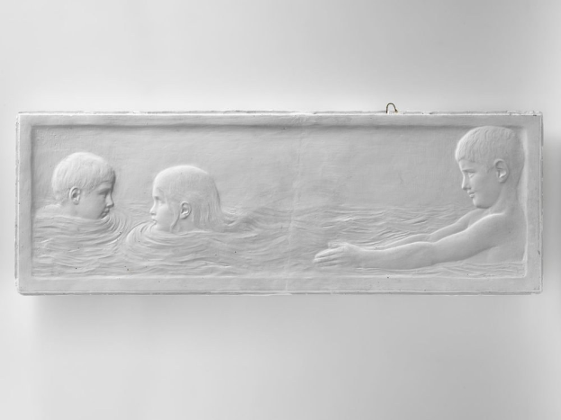 Drei Kinder schwimmen in einem Pool mit einer Wand im Hintergrund.