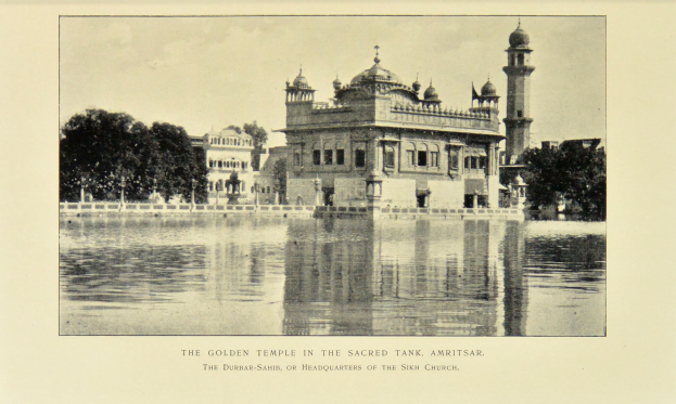 Der goldene Tempel in Amritsar ist von Wasser, Bäumen und einem klaren Himmel umgeben und zeigt unten im Bild Text.