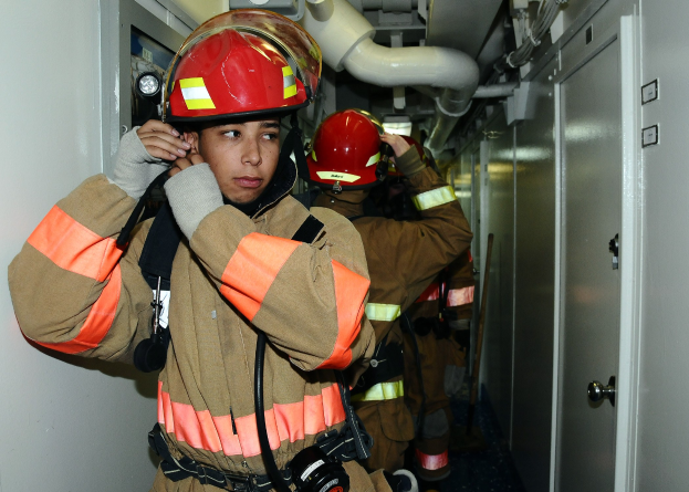 Feuerwehrleute in Uniform während einer Übung in einem Raum mit Rohren und Geräten