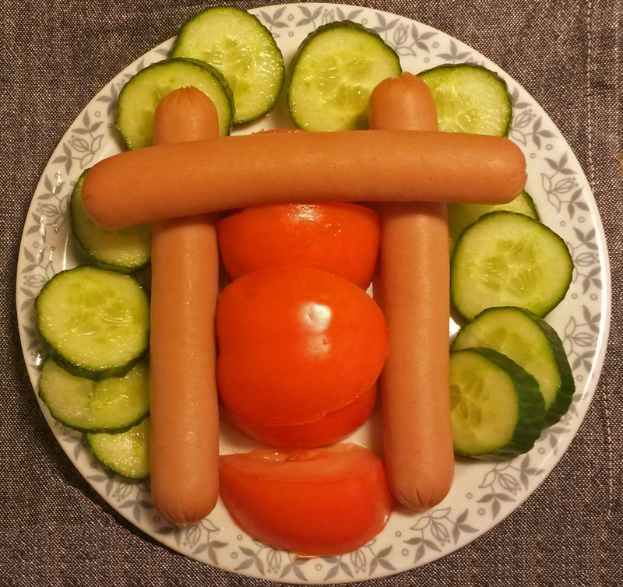 Ein Teller mit einer Vielfalt an Gemüse, einschließlich Tomaten und Gurken, in Form einer Wurst angeordnet.